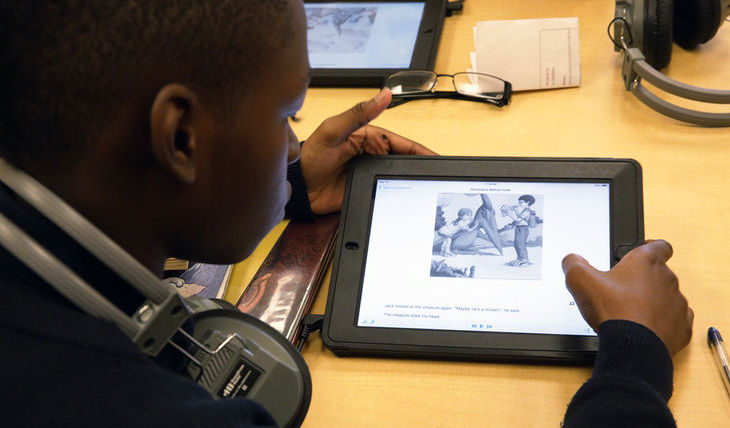 Student reading Learning Ally audiobook on tablet